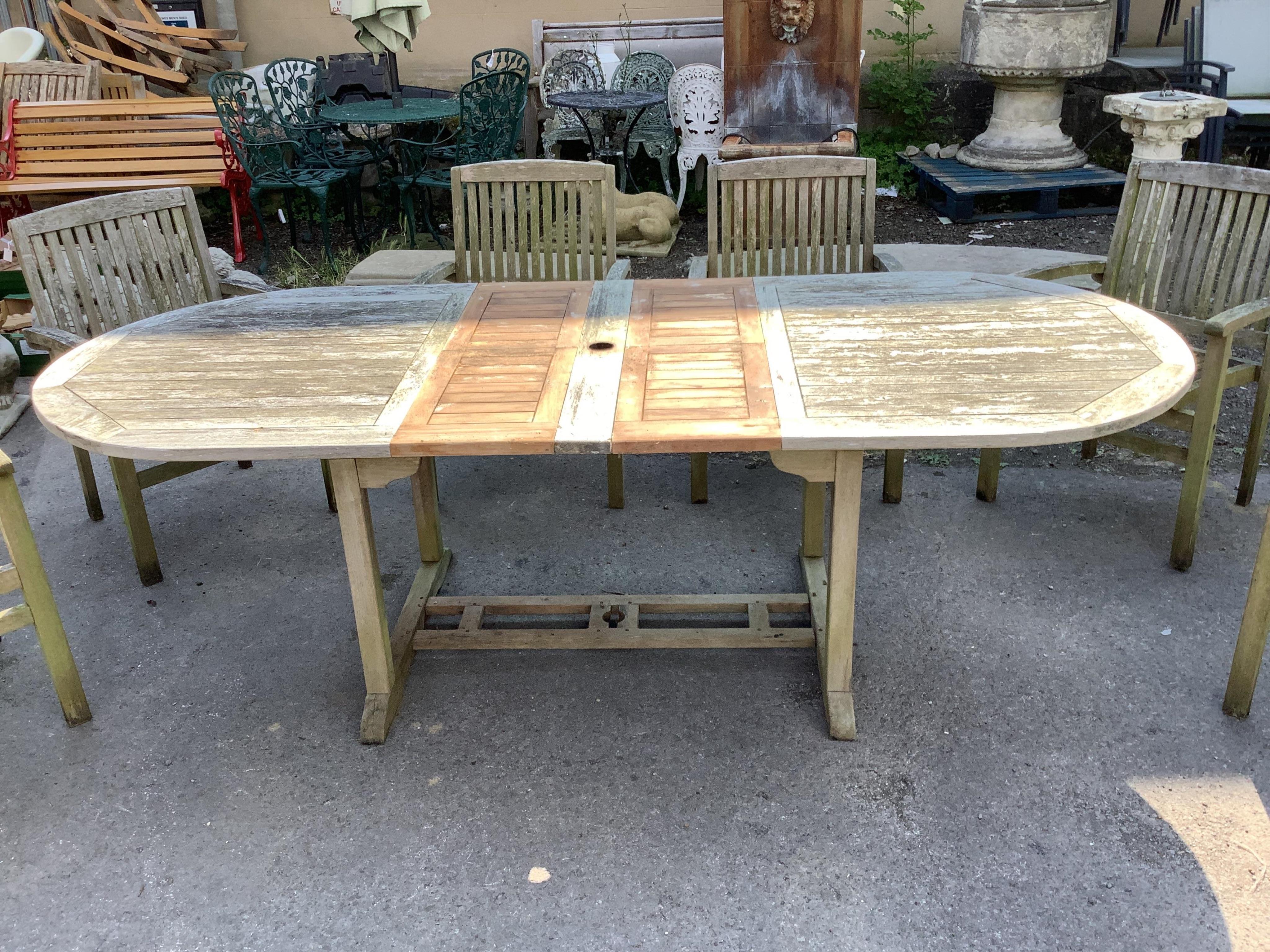 A “Kyoto” weathered teak extending garden table, width 240cm extended, depth 100cm, height 75cm, together with six stacking elbow chairs. Condition - fair